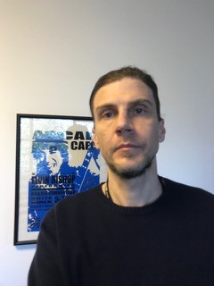 There is a photo of Drew with a somewhat serious face, posing in front of a framed concert poster that says “ASCAP” on it