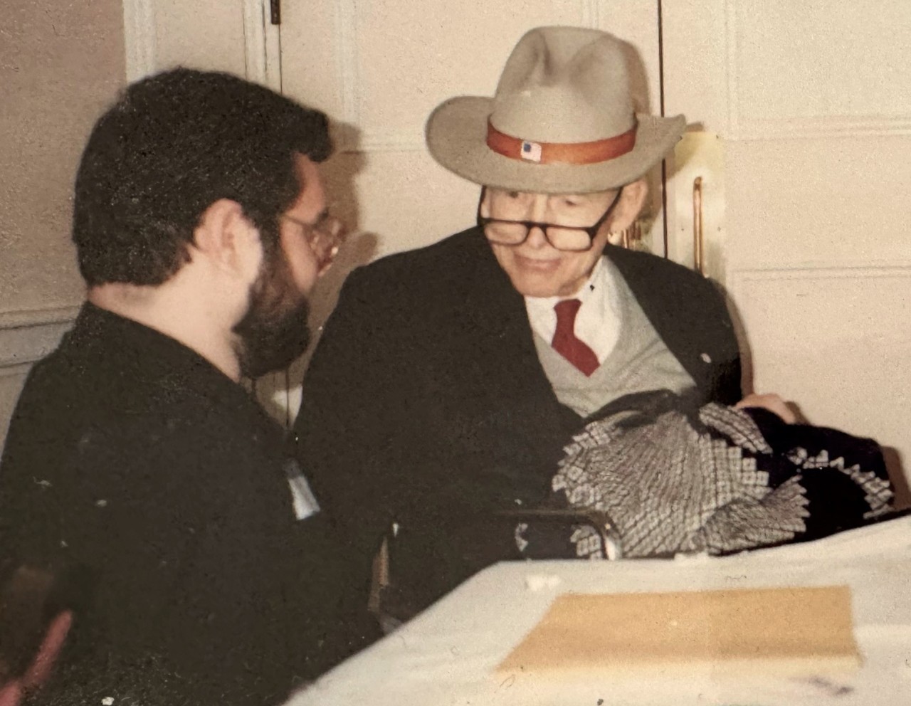 Kevin Wright and Justin Dart A banner photo at the beginning of the article shows a young, white man with dark hair and beard and glasses seated with an older, white man wearing a tan hat, reading glasses, and a tie, sweater vest, and suit jacket.