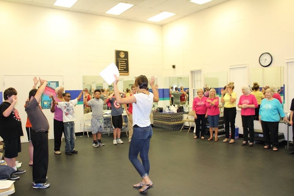 a female instructor leading youth participants and volunteers in a game