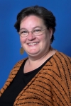 headshot of JoEllen Fowler, a white woman with short brown hair and an orange striped knit sweater and black blouse, glasses and gold earings