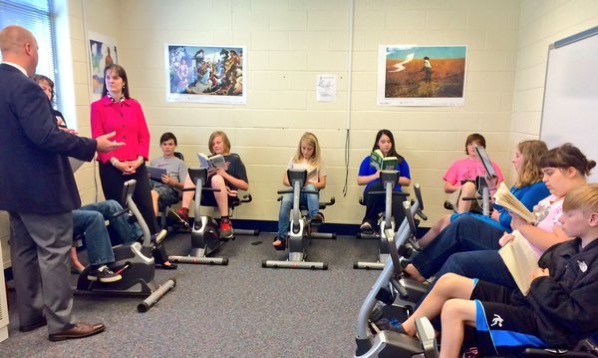 Students reading while on exercise bikes