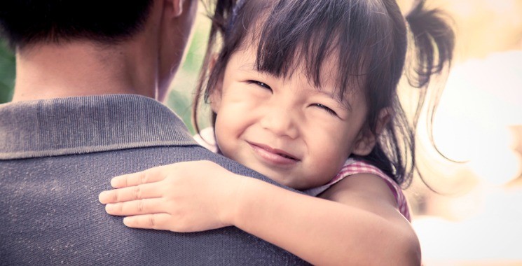 Father and child,happy little girl resting on her father's shoulder in the park, vintage filter effect